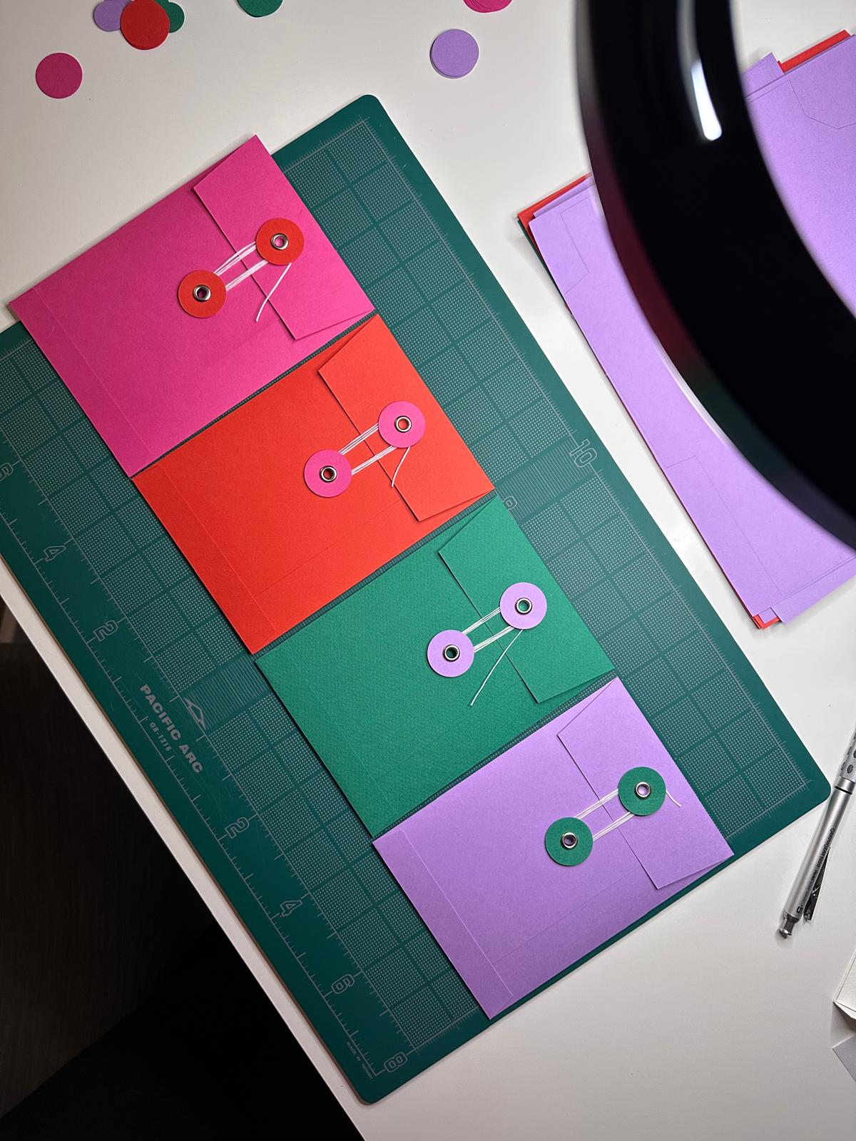 Hand-folded envelopes in the mail club's colors, sealed with a button and thread closure